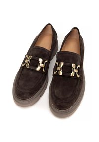 Zamszowe loafers w ciemnym brązie z grubą podeszwą. Posiadają dekoracyjną klamrę w złotym kolorze na cholewce. Gładka skórzana podszewka wewnętrzna.