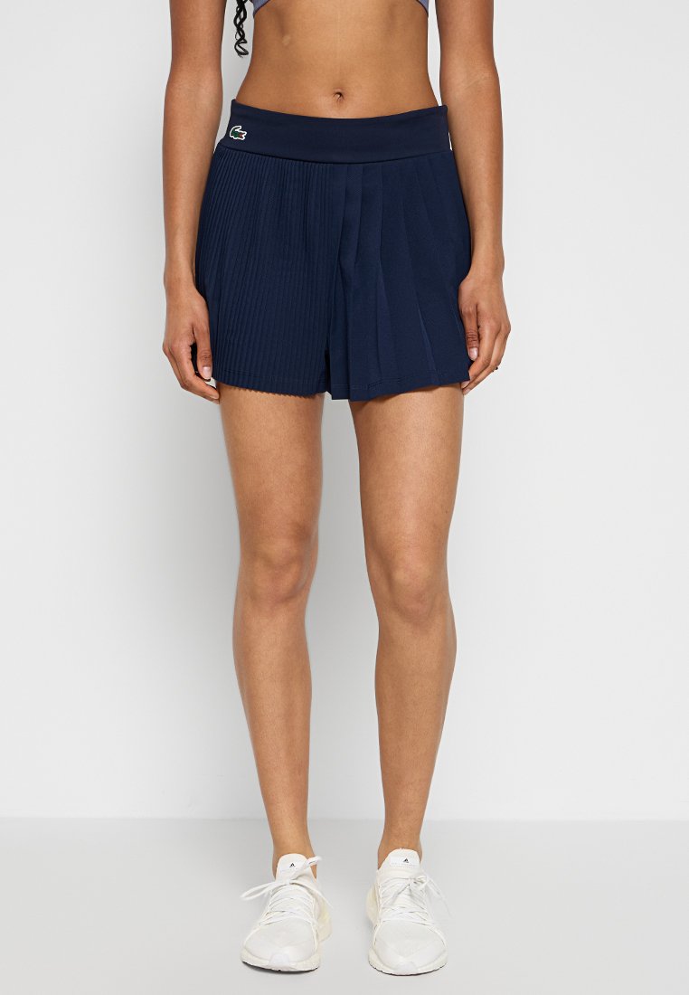 Granatowe szorty z plisami, wykonane z lekkiego materiału, z szerokim pasem z logo. Zaprojektowane z myślą o komforcie i swobodzie ruchów.