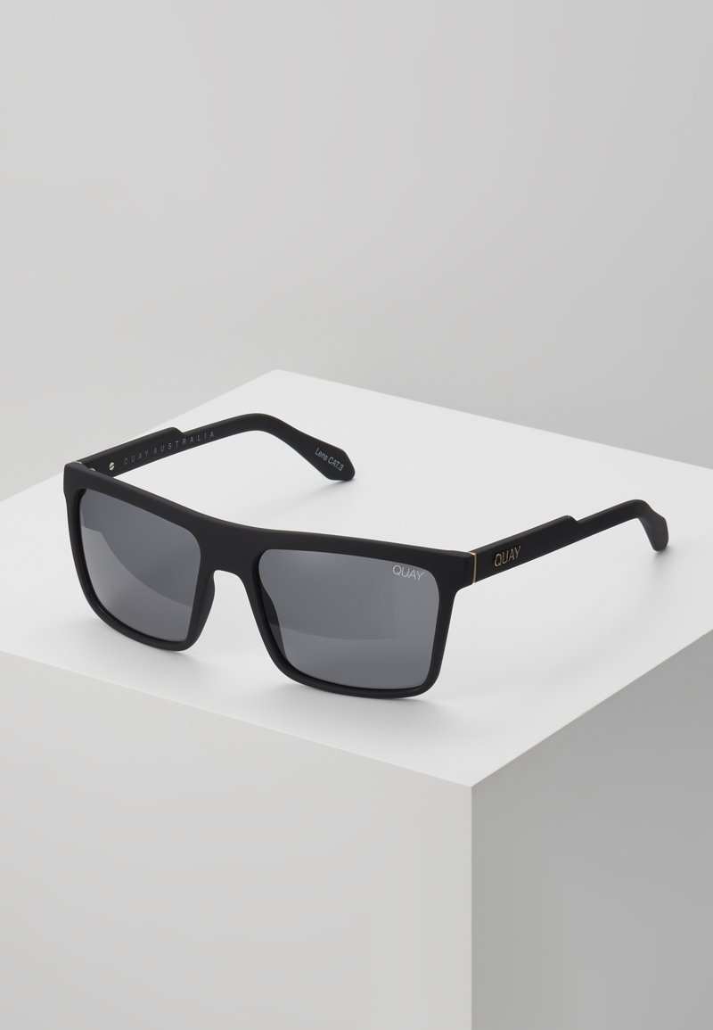 Ochelari de soare rectangulari negri cu lentile închise, textură mată și accente aurii pe brațe. Prezintă branding gravat pe laturi.
