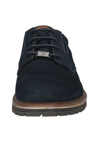 Chaussure en daim bleu foncé avec un bout arrondi, six œillets et un support de lacet en argent. La semelle est en caoutchouc texturé avec un accent en bois.