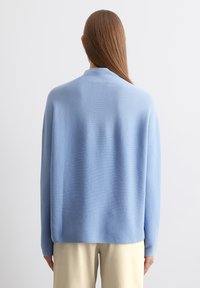 Helles blaues Sweatshirt aus weichem Stoff, mit legerem Schnitt, langen Ärmeln und einem schlichten Rundhalsausschnitt. Glatte Textur, minmale Details.