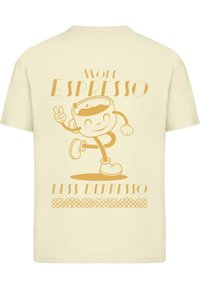Cremefarbenes T-Shirt mit einem verspielten Kaffeetassen-Charakter und dem Text „More Espresso Less Depresso“ in gelb-orangener Typografie.