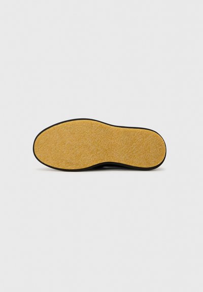 Semelle de chaussures noire avec une surface en liège jaune texturé. Présente des bords arrondis et une fine bordure noire autour de la semelle.