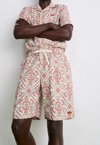 Ensemble à manches courtes à motifs dans des couleurs pastel claires, présentant des dessins géométriques complexes, avec une taille élastique et un cordon de serrage.