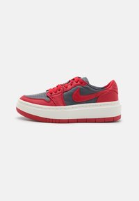 Baskets basses avec tige en cuir rouge et gris foncé, lacets rouges, logo Nike et semelle en caoutchouc épaisse blanche et rouge sur fond blanc.