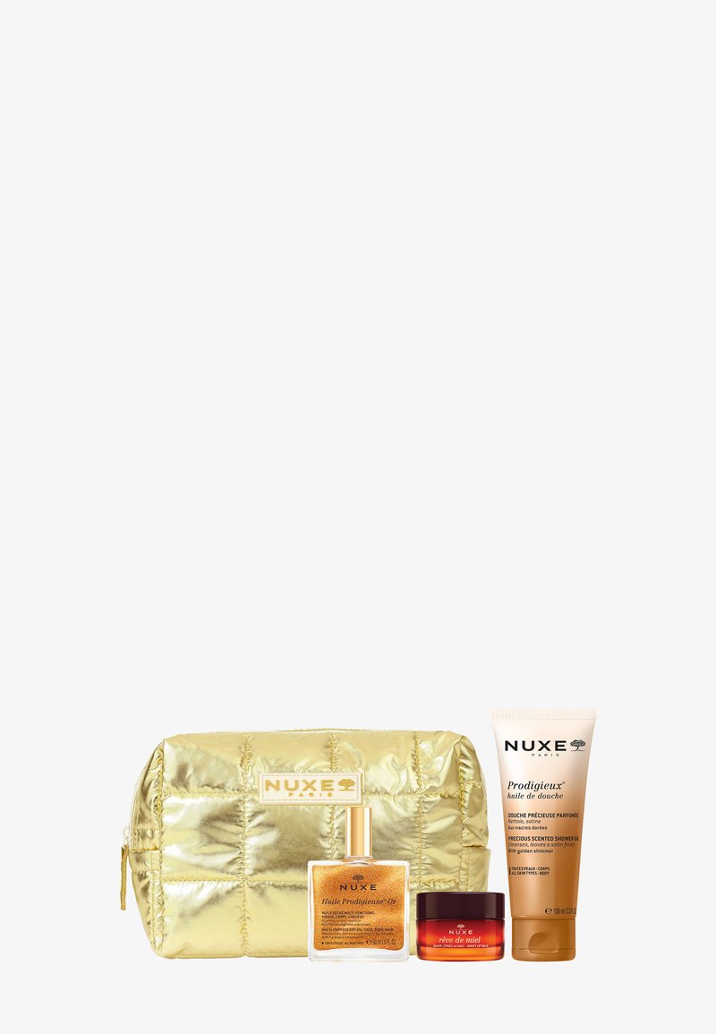 Gouden gewatteerde make-up tas met drie NUXE Paris huidverzorgingsproducten: glinsterende olie, rode crèmepot en tube douchegel.