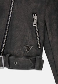 Chaqueta negra de cuero sintético con cremalleras plateadas, parche de logo triangular y cintura con cinturón y acabado texturizado.