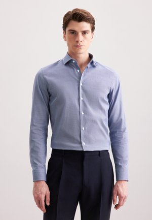 Himmelblaues Button-Up-Hemd mit strukturiertem Muster, langen Ärmeln und weißen Knöpfen, kombiniert mit dunklen Hosen.