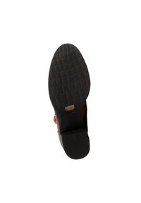 Semelle d'une chaussure en cuir marron avec une semelle extérieure en caoutchouc noir texturé et une petite étiquette dorée près de la zone de la voûte plantaire.