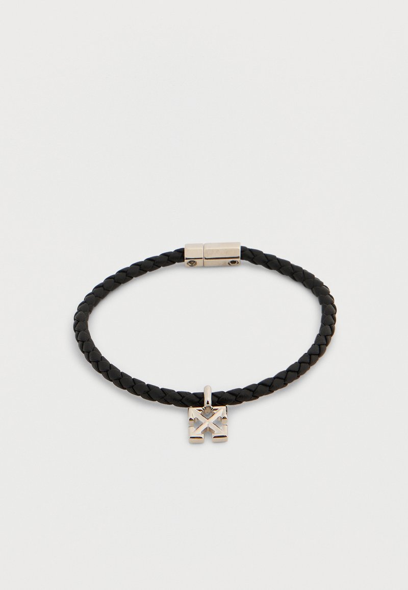 Bracelet en cuir noir tressé avec fermoir magnétique argenté et petit pendentif carré en argent présentant un motif géométrique gravé.