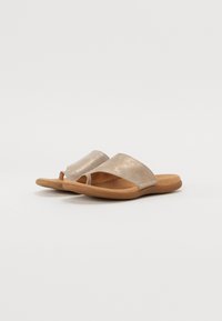 Sandali in metallo dorato con design a fascia incrociata, punta aperta e suola interna morbida color tan. Presentano una superficie liscia e dettagli di cucitura minimi.