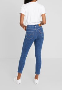 Vaqueros ajustados azules con acabado desvaído, cintura alta y costuras en contraste. Presentan dos bolsillos traseros y una etiqueta de cuero con la marca en la cintura.