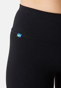 Leggings neri con una texture liscia, dotati di un piccolo etichetta della bandiera svedese blu e gialla sulla vita.