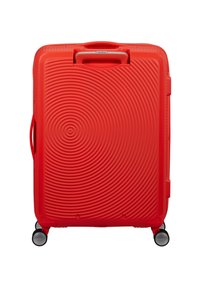 Valigia rigida rossa con motivo a cerchi concentrici, manico telescopico, manico laterale e quattro ruote girevoli su sfondo bianco.