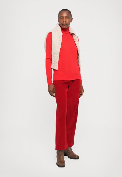 Red long-sleeve sweater, beige textured vest, and red wide-leg corduroy pants. Brown ankle boots. Simple, fitted design with contrasting tones.