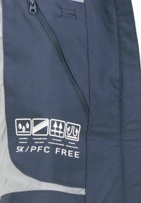 Mörkblå jacka med dragkedja, visar symboler för vattentålighet, bandsydda sömmar, fuktgenomsläpp, vindskydd och texten "5K / PFC GRATIS".