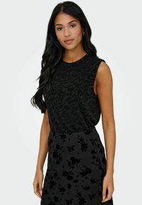 Czarny top bez rękawów z teksturowanym wzorem, w połączeniu z czarną spódnicą z kwiatowym welurowym nakładaniem. Prosta sylwetka i elegancki design.