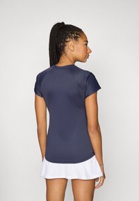 Camiseta deportiva azul marino con mangas cortas, textura acanalada y diseño ajustado, combinada con una falda blanca acampanada.