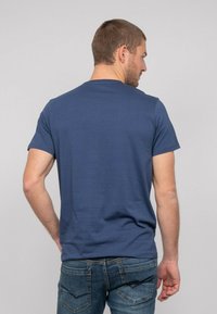 T-shirt bleu marine à manches courtes en tissu doux, avec un col rond et une coupe décontractée, associé à un jean en denim délavé.