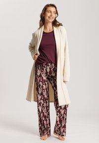 Crème lange open cardigan, bordeaux top en gepatternde broek met paisley design in bordeaux en roze tinten. Zachte stof, ontspannen pasvorm.