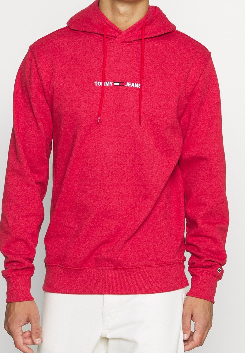 Sudadera roja con capucha de tejido texturizado, que presenta un logo blanco en el pecho. Incluye cordones y puños acanalados.