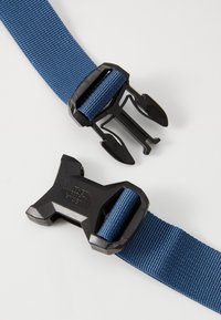 Kék nylon heveder fekete műanyag csattal, amelyen logó található. A heveder lapos, texturált felületű, amely biztosítja a tapadást és a tartósságot.
