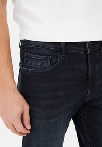 Donkerblauwe spijkerbroek met een slim fit, met een textuur detail op de zak en een enkele knoopsluiting bij de taille.