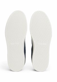 Granatowa podeszwa butów z białą gumową podstawą. Posiada teksturowaną powierzchnię z diamentowymi wzorami oraz wytłoczonym logo „TOMMY JEANS”.