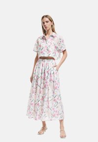 Blomster crop-top skjorte og lang nederdel s�æt i hvid, med rosa blomster og grønne blade. Letvægtsstof med en afslappet pasform.