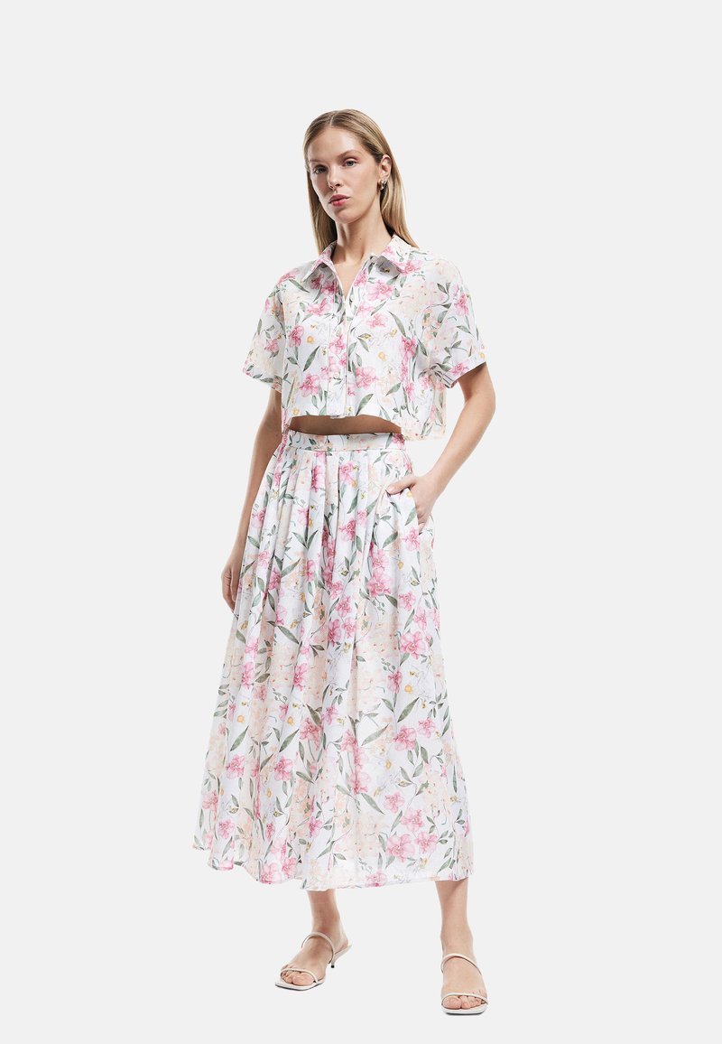 Blomster crop-top skjorte og lang nederdel sæt i hvid, med rosa blomster og grønne blade. Letvægtsstof med en afslappet pasform.