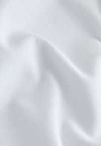 Gros plan d’un tissu blanc et doux avec des plis subtils et une texture tissée fine, mettant en valeur une surface de matériau lisse et propre.