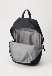 Black backpack with a zip closure, featuring a smooth, shiny gray interior and front pocket, designed with a top handle for easy carrying.