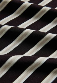Black fabric with evenly spaced white vertical stripes, shown with soft folds and visible texture.
