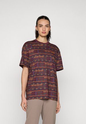 Kortermet, maroon mønstrete T-skjorte med geometriske design i blå, gul og grønn. Myk tekstur, avslappet passform, rund hals.