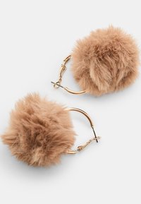 Orecchini a cerchio in pelliccia sintetica con morbidi pom-pom color beige, con hardware dorato e chiusura a clip per un facile utilizzo.