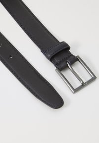 Ceinture en cuir bleu marine avec une surface lisse, dotée d'une boucle en métal argenté à forme carrée et d'un seul passant, avec des trous régulièrement espacés.