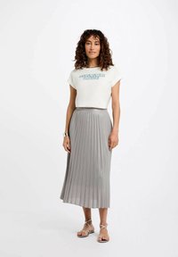 Gonna midi grigia plissettata con una texture lucida, abbinata a una t-shirt bianca a maniche corte con il testo blu "SUMMER LOVE". Sandali piatti completano il look.