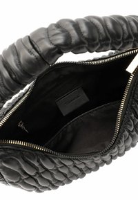 Sac à main en cuir noir avec une texture matelassée, doté d'une anse tressée. L'intérieur comprend une doublure noire et une poche zippée.