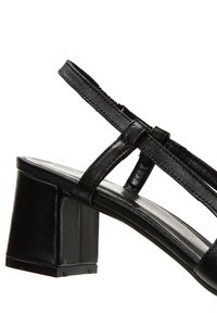 Sandalía de bloque de tacón en cuero negro con correas delgadas ajustables, plantilla texturizada y un diseño de tacón cuadrado.