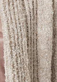 Beige knitted textile with a soft, fuzzy texture, featuring vertical ribbed and woven patterns. Suitable for warm clothing or accessories.