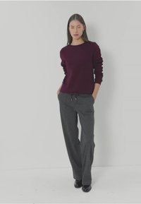 Bordeaux gebreide trui met lange mouwen, gecombineerd met grijze losse pantalon met een elastische tailleband en trekkoorddetail.