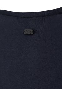 Tissu bleu marine avec une petite étiquette noire près de l'encolure embossée de "POLO CLUB" en lettres majuscules.