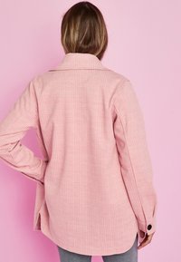 Roze geruit overshirt van een gestructureerde stof, met een kraag, lange mouwen en zijopeningen, en een knoopdetail aan de manchetten.