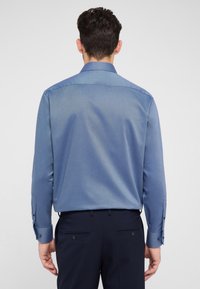 Blauwe lange mouwen overhemd met een gestructureerd patroon, met knoopmanchetten en een spitse kraag, gecombineerd met donkere broeken.