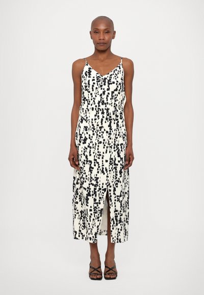 Robe midi à motifs noir et blanc avec un décolleté en V, des bretelles fines et une fente sur le côté, fabriquée à partir d'un tissu léger au toucher doux.