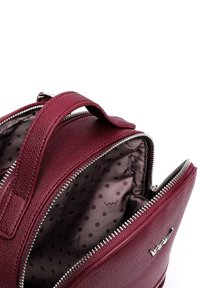 Burgundy leather bag with a grainy texture, zippered opening, and interior featuring a brown dot pattern. Includes a top handle for carrying.