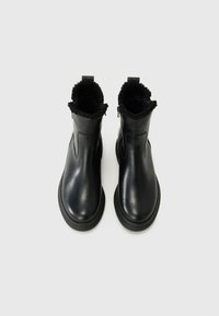 Zwarte leren enkelboots met een gestructureerde stof manchette, ronde neus en een stevige rubberen zool. Ritsdetail aan de zijkant.