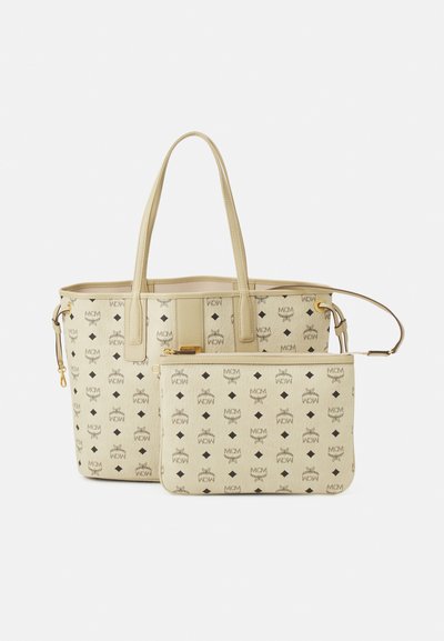 Sac fourre-tout beige avec deux poignées, arborant un motif de logo répété en noir. Inclut une pochette assortie avec une fermeture éclair dorée.