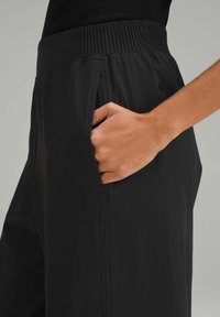 Zwarte relaxte broek van lichtgewicht stof, met een elastische tailleband en zijzakken met zichtbare stikdetails.