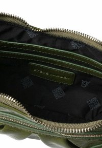 Grøn lædertaske indvendig med en struktureret overflade, der har mørk foring og lynlås. Inderlappen og rum er synlige.